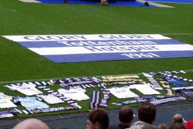 A poignant flag is laid out between the stage and the many fans' tributes
